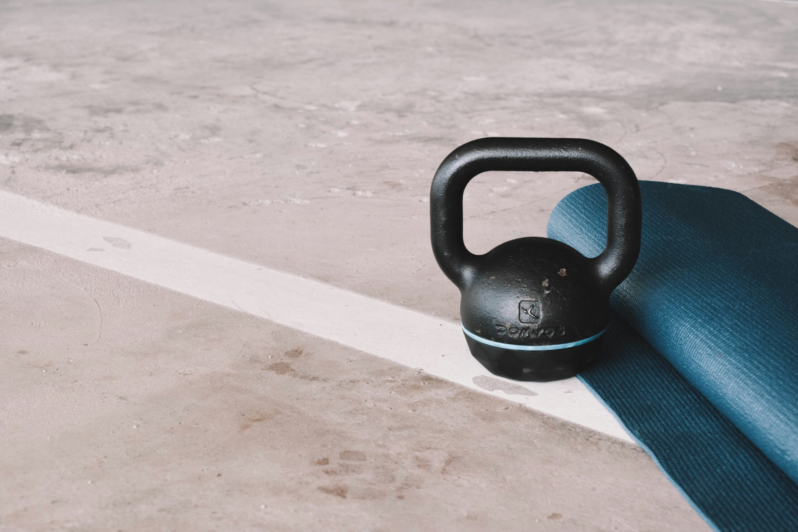 A person swinging a kettlebell outdoors in sunlight.