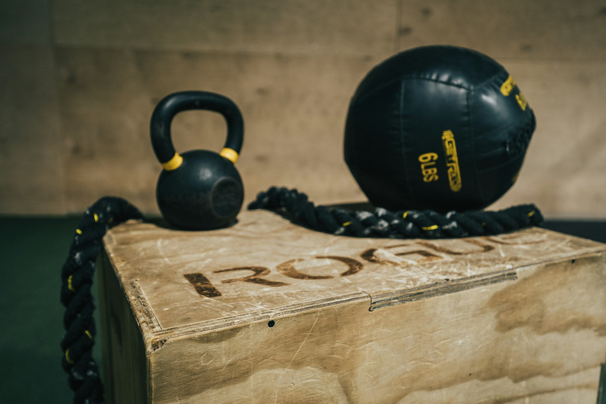 A close-up shot of a black cast iron kettlebell resting on a wooden floor.