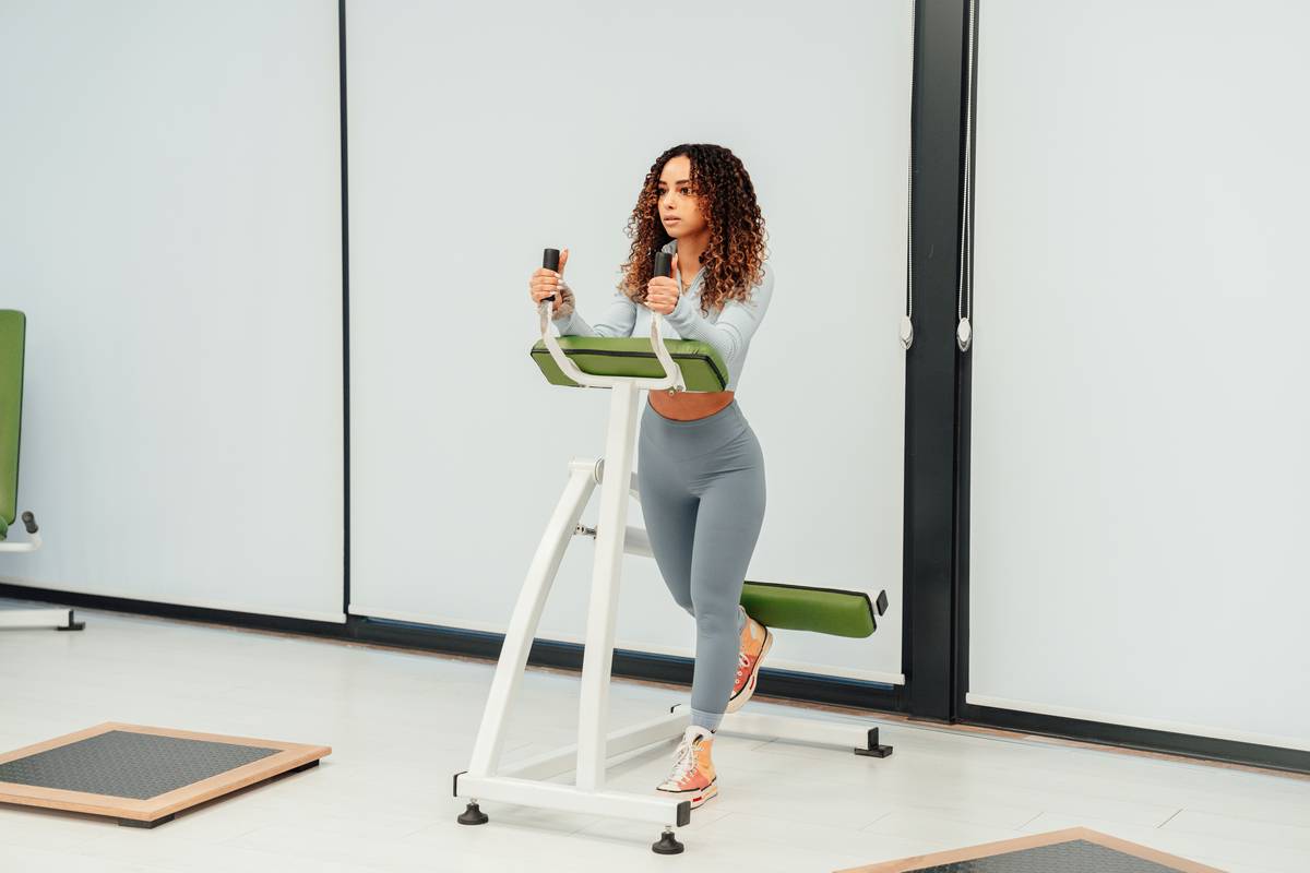 A woman demonstrating proper kettlebell swing form in a gym setting.