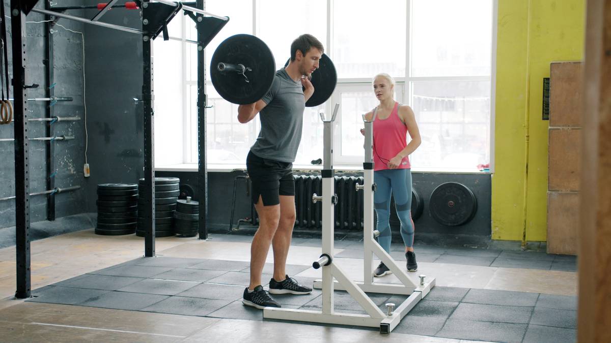 A person holding a kettlebell mid-swing at a gym.